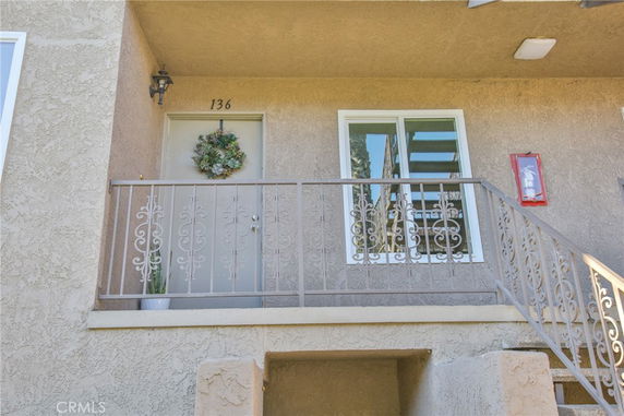 Front view of a building entry with a decorative railing and wreath on the door.