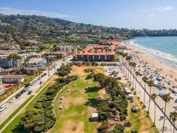 Panoramic view of a coastal area with a beach, buildings, and greenery.