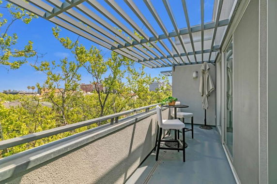 View from a balcony with a small table and chairs, overlooking trees and distant buildings.