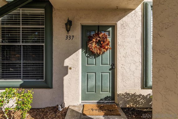 Front view of a house entrance with a green door adorned with a decorative wreath.