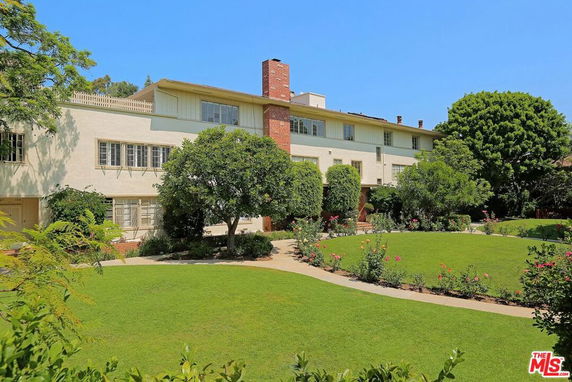 Front view of a multi-story house with a chimney and large windows.