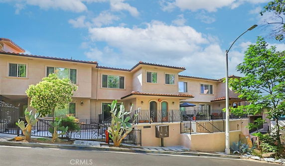 Front view of a multi-story townhouse with a gated entrance and tile roof.