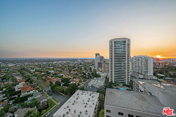 Panoramic view of a cityscape with tall buildings and a sunset horizon.