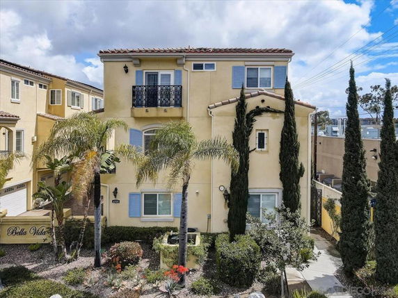 Front view of a multi-story house with decorative balcony and blue shutters.