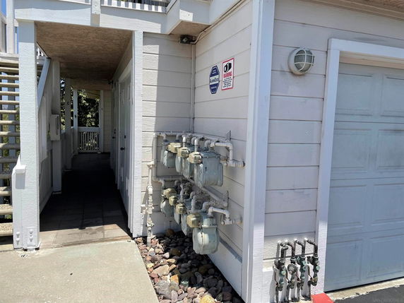 Side view of a building showing multiple utility meters and a garage door.