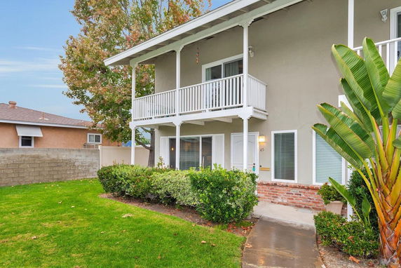 Front view of a two-story house with a balcony and white railings.