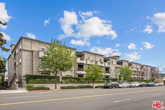 Front view of a multi-story apartment building along a street.