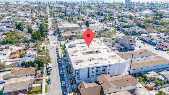 Aerial view of a multi-story building with a flat rooftop in a residential area.