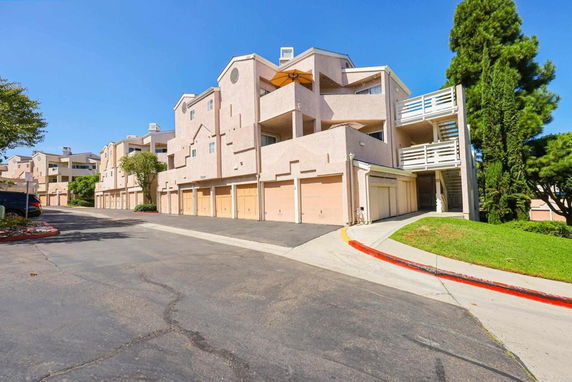 Front view of a multi-story residential building with garages on the ground floor.