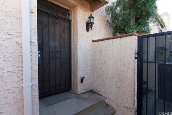 Entrance view of a house with a metal security door and exterior wall light.