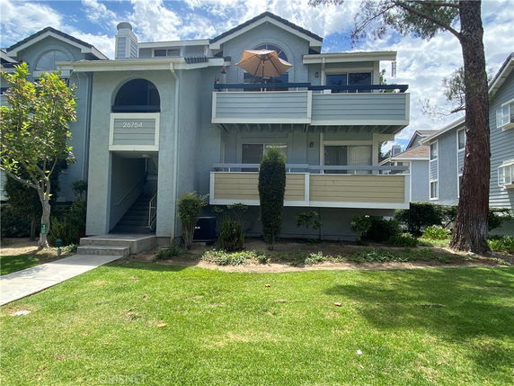 Front view of a multi-story house with balconies and a central entrance.