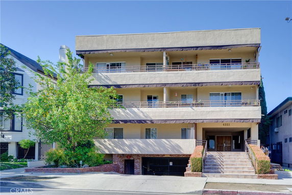 Front view of a three-story apartment building with a staircase leading to the entrance.