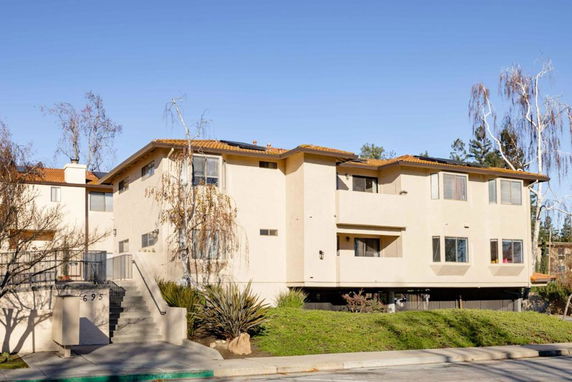 Front view of a two-story residential building with a staircase leading to the entrance.