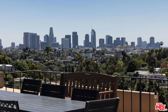 Panoramic view of city skyline from an outdoor terrace with furniture.