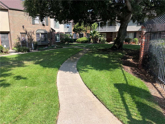 Front view of a multi-story house with a pathway and greenery.