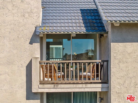 Front view of a building section with a balcony and sliding glass doors.