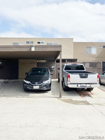 Covered parking area with two parked vehicles in front of a building.