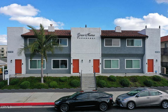 Front view of a two-story townhouse building with a central entrance and red doors.