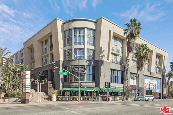 Front view of a multi-story commercial building with shops and restaurants at the ground level.