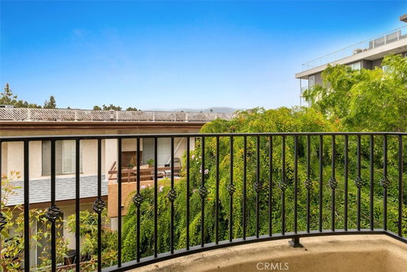 View from a balcony overlooking a building with solar panels and surrounding greenery.