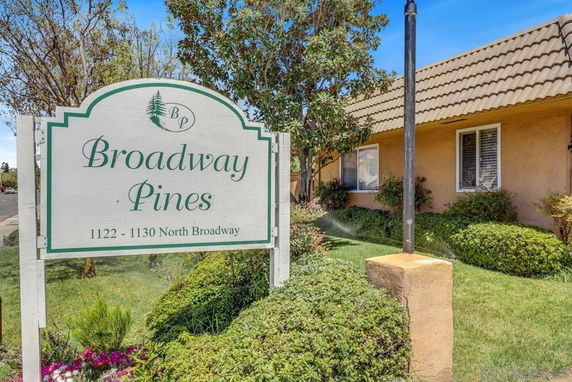 Front view of a building with a tiled roof and windows, next to a sign reading 'Broadway Pines'.