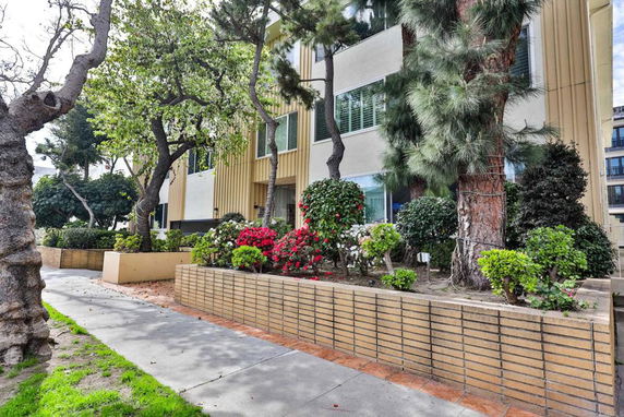 Front view of a multi-story building with planted trees and flowers.