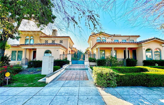 Front view of adjacent two-story houses with tiled roofs and arched windows.