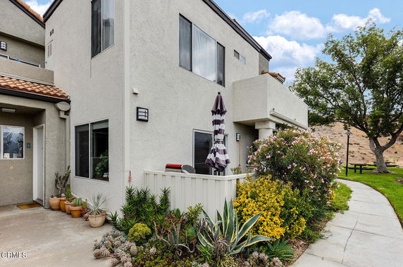 Front view of a two-story house with a small patio and potted plants.