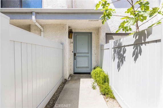 Front view of a house with a white fence and a blue door.