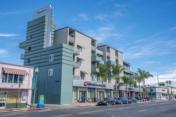 Front view of a multi-story building with balconies and street-level shops.