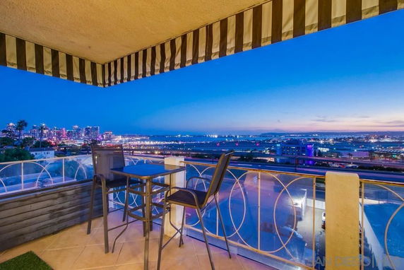 Outdoor balcony view overlooking a city skyline at dusk.