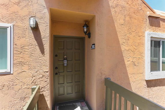 Front entrance of a building with a textured wall and green door.