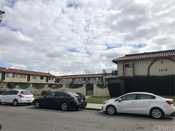 Front view of a two-story apartment building with tiled roofs and a gated entrance.