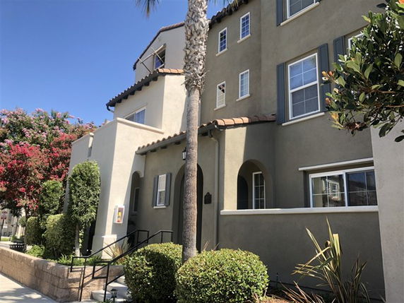 Front view of a multi-story house with arched entry and shutters.