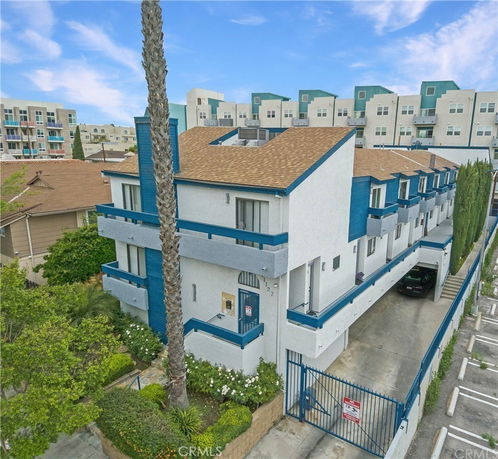 Front view of a multi-story residential building with blue accents and a gated entrance.