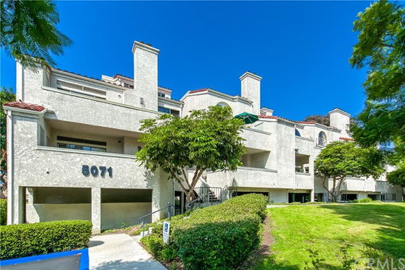 Front view of a multi-story building with chimneys and a garage area.