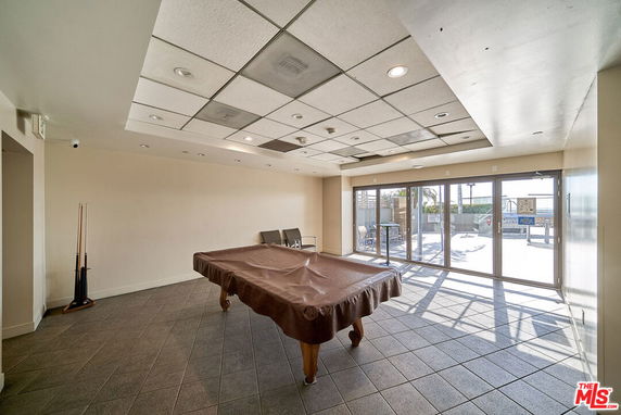 Indoor room with a covered pool table and tiled floor.