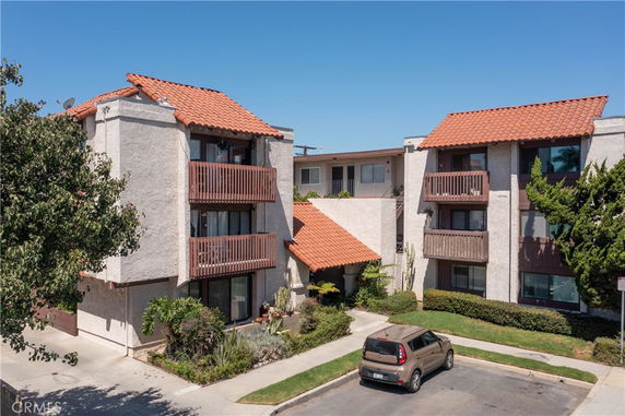 Front view of a multi-story apartment building with balconies and red-tiled roofs.