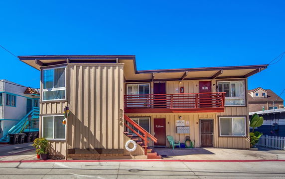 Front view of a two-story building with balconies and numbered doors.