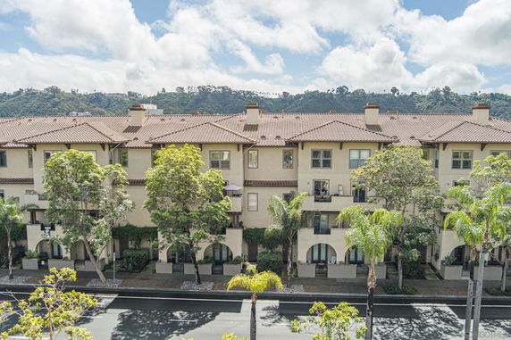 Front view of a multi-story residential building with arches and balconies.
