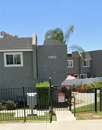 Front view of a multi-story residential building with a fence and gate.