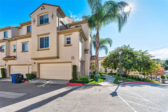 Front view of a multi-story house with a double garage and Mediterranean-style architecture.