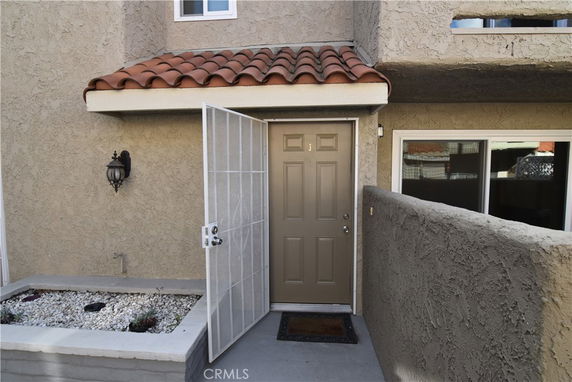 Entrance view of a house with a tiled roof and beige stucco walls.