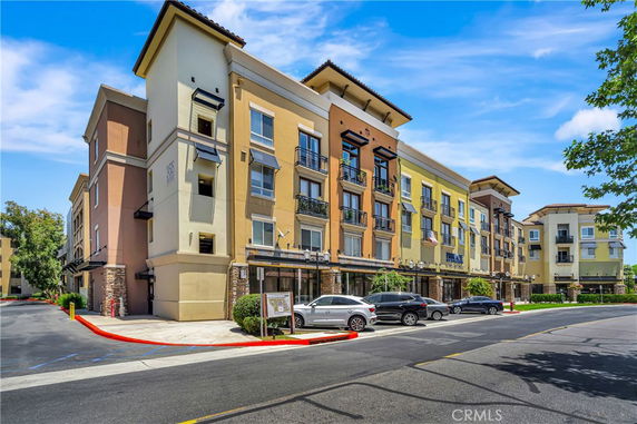 Front view of a multi-story residential building with parking area in front.