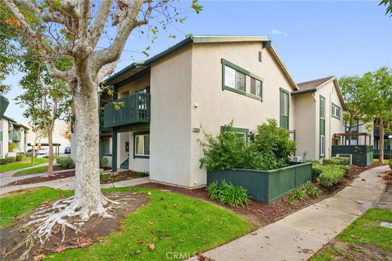 Front view of a two-story residential building with an external staircase and green trim.