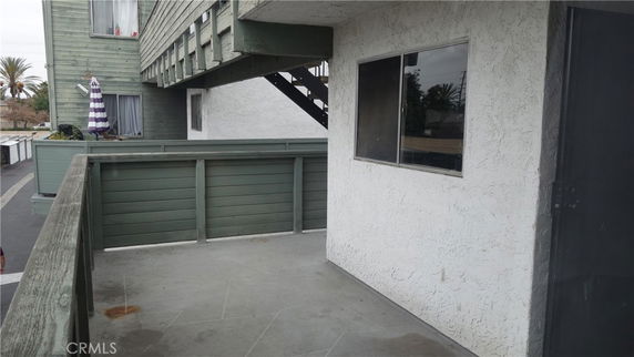 View of a building's exterior with green wood siding and a concrete balcony area.