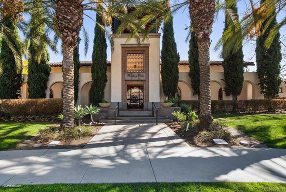Front view of a building with arched doorways and tall trees.