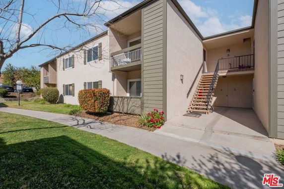 Front view of a two-story apartment building with exterior staircases and balconies.