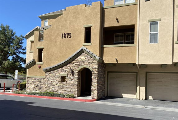 Front view of a multi-story building with a stone entrance and two garages.