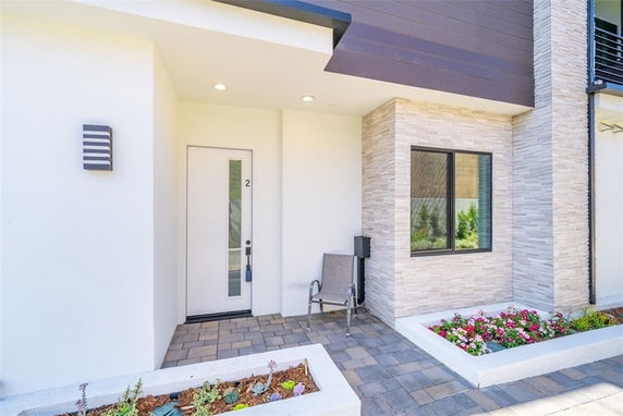 Front view of a modern house with a door and window, featuring stone and brick accents.